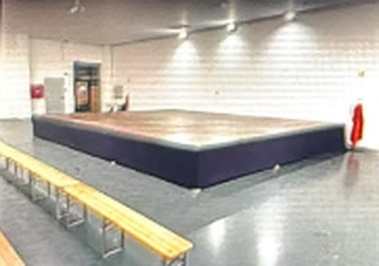 Estrado técnico com saia escura montado num pavilhão desportivo